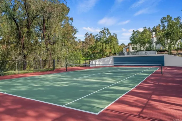 a view of a tennis ground with large trees