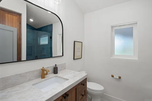 a bathroom with a granite countertop toilet sink and mirror
