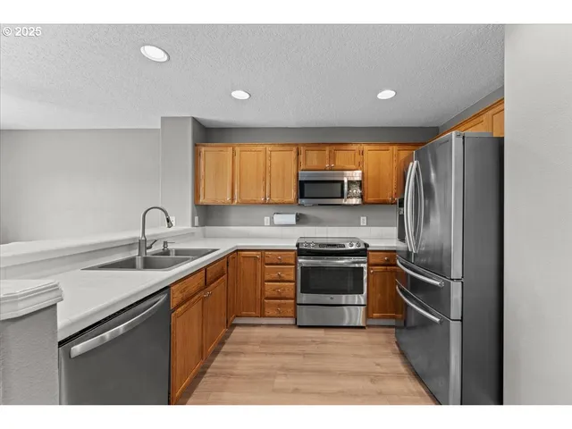 a kitchen with stainless steel appliances granite countertop a sink a stove a microwave a counter top space and cabinets