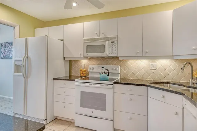 a kitchen with granite countertop white cabinets and refrigerator