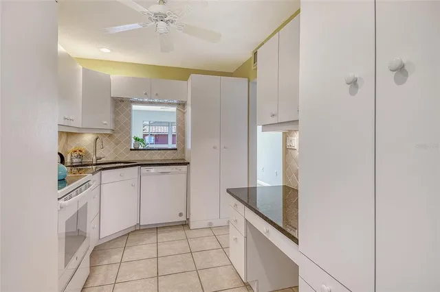 a kitchen with granite countertop white cabinets and white appliances