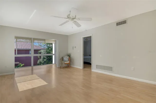 a view of an empty room with a window and wooden floor