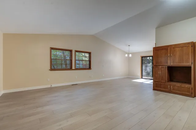 an empty room with wooden floor fireplace and windows