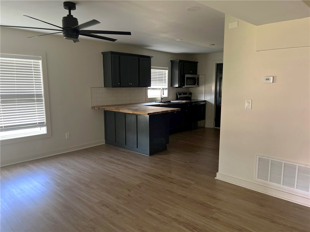 4501 College Main Street, Unit 1 Bryan, TX 77801 - Photo 4 of 8 a kitchen with stainless steel appliances granite countertop a stove and a wooden floors