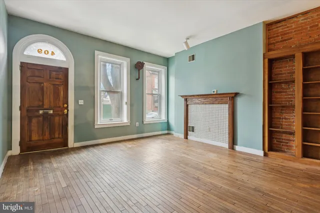 an empty room with wooden floor closet and windows