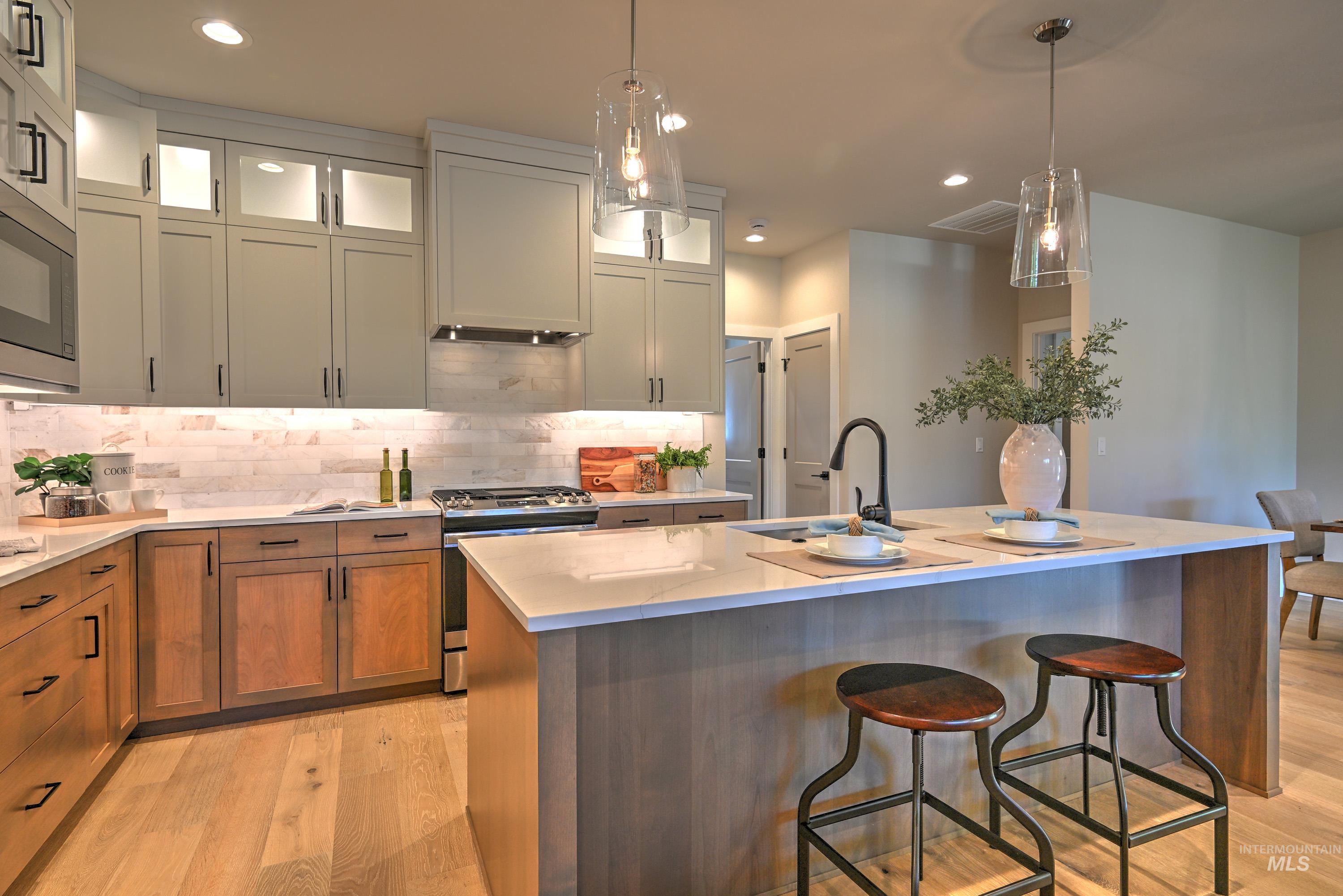1469 North Parkshire Way Meridian, ID 83642 - Photo 18 of 43 Kitchen with appliances with stainless steel finishes, light wood finished floors, tasteful backsplash, recessed lighting, and a kitchen breakfast bar