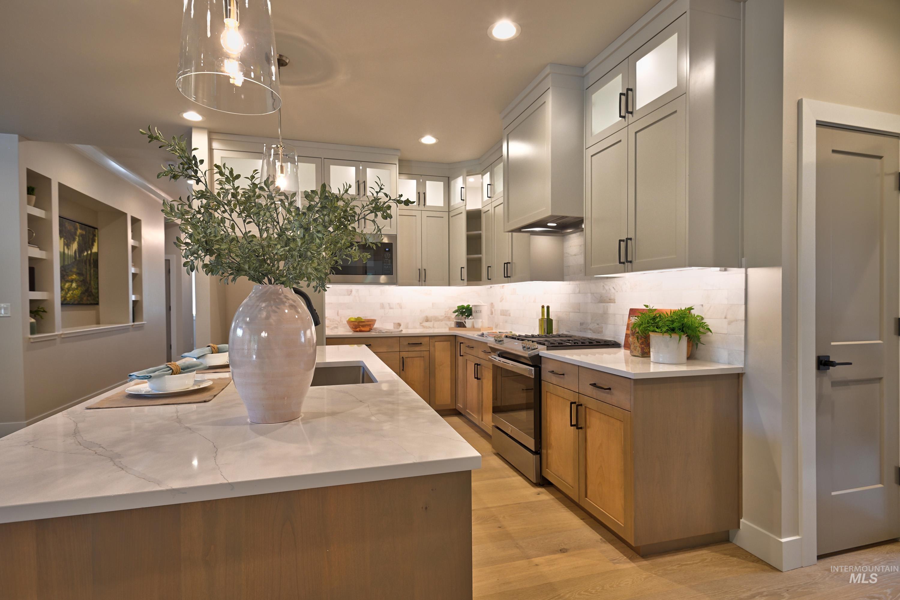 1469 North Parkshire Way Meridian, ID 83642 - Photo 20 of 43 Kitchen featuring stainless steel range with gas stovetop, decorative backsplash, light wood finished floors, wall chimney range hood, and recessed lighting
