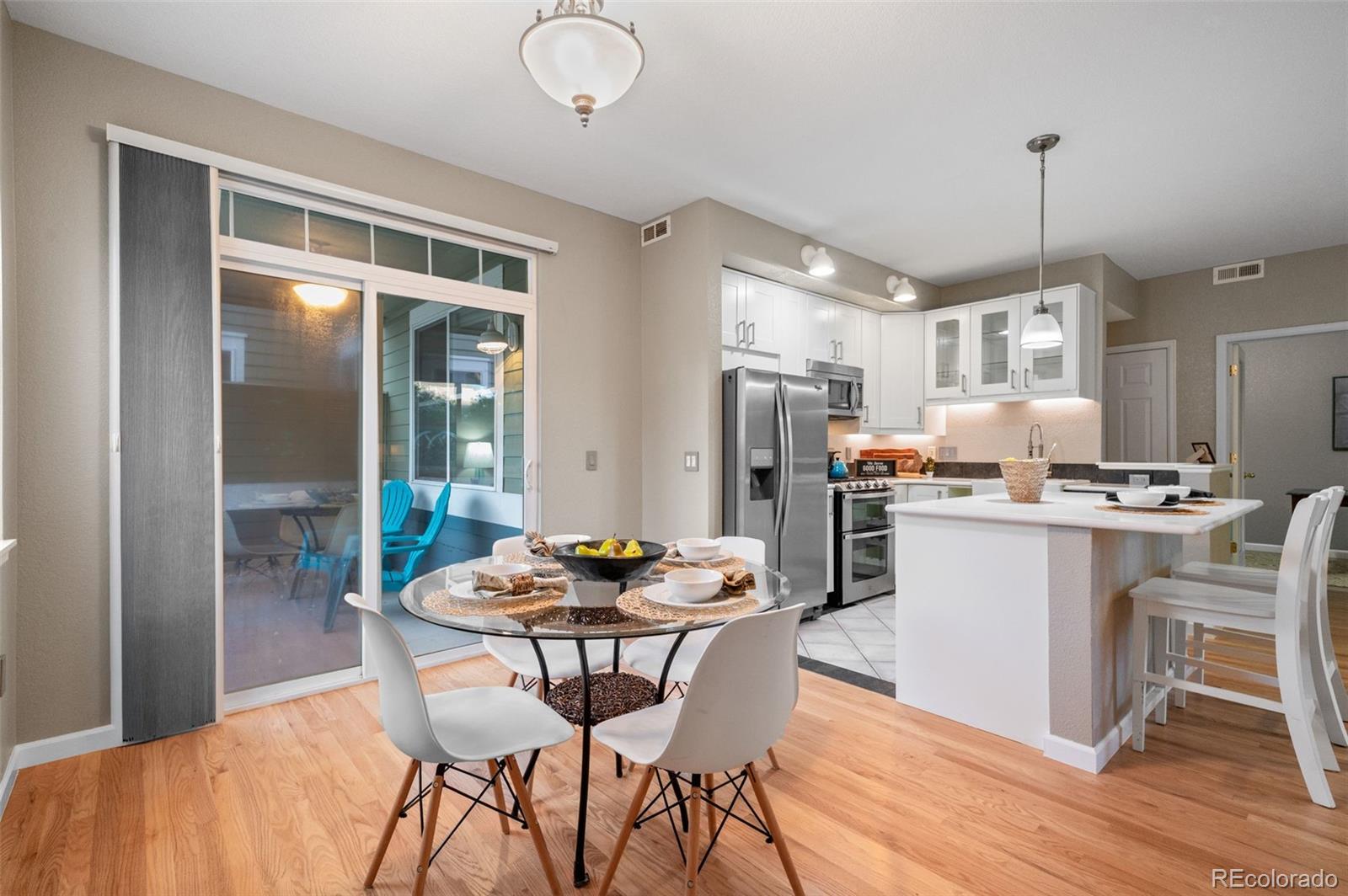 4501 Nelson Road, Unit 2104 Longmont, CO 80503 - Photo 8 of 29 a kitchen with a dining table chairs refrigerator and wooden floor