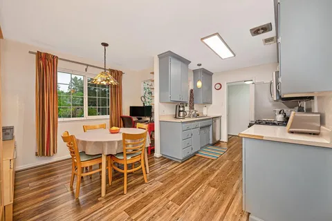 a dining hall with stainless steel appliances kitchen island granite countertop furniture and wooden floor