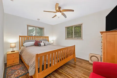 a bedroom with a bed a couch and a flat tv screen on the dresser