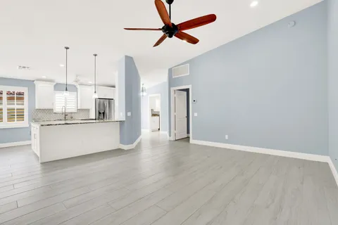 a view of kitchen with stainless steel appliances granite countertop a refrigerator a sink dishwasher a stove and white countertops with wooden floor