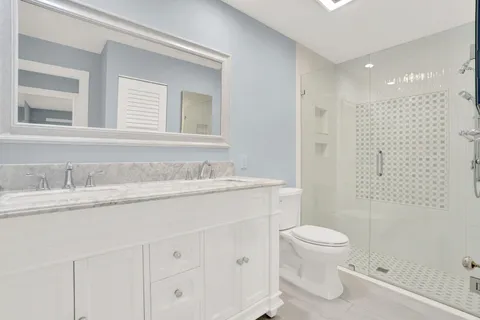 a bathroom with a granite countertop sink a toilet and a shower