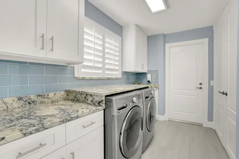 a utility room with granite countertop cabinets washer and dryer
