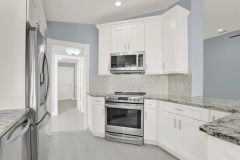 a kitchen with granite countertop a stove top oven microwave and refrigerator