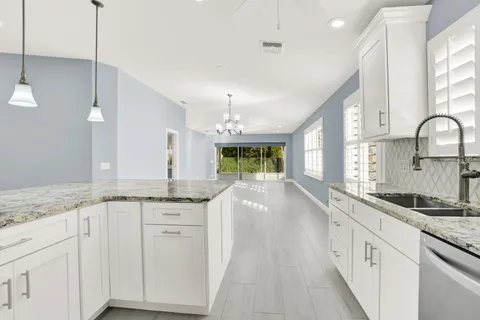 a kitchen with granite countertop a sink and white cabinets