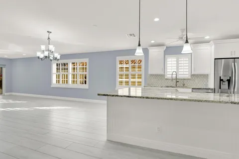 a large kitchen with granite countertop a stove a sink a center island and couches