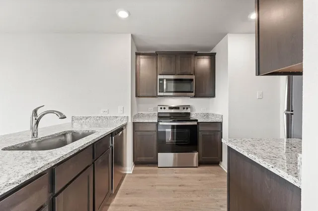 a kitchen with stainless steel appliances granite countertop a sink stove and refrigerator