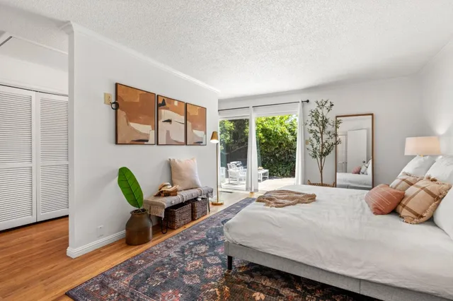 a bedroom with a bed a large window with table and chair