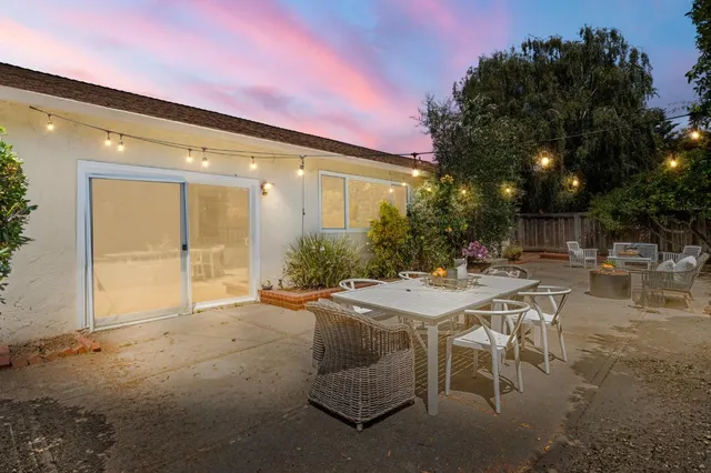 a view of a patio with table and chairs and potted plants with wooden fence