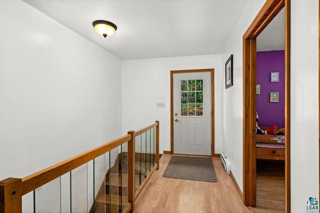5466 Jean Duluth Road Duluth, MN 55803 - Photo 14 of 34 Wood-finish flooring throughout, solid wood railing with glass balusters, and a white paneled door with window inserts