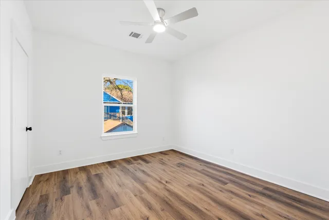 an empty room with a window and ceiling fan