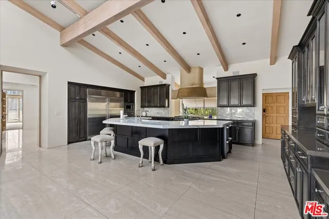 a kitchen with stainless steel appliances kitchen island granite countertop a refrigerator a sink dishwasher a stove and a dining table with wooden floor