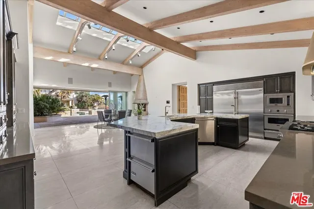 a view of a kitchen with kitchen island a counter top space a sink stainless steel appliances and cabinets