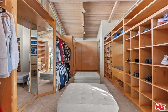 a view of walk in closet with clothes and shoes