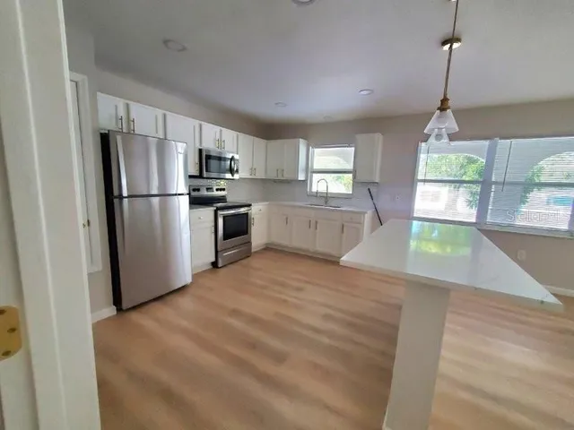 a view of kitchen with stainless steel appliances refrigerator stove microwave and cabinets