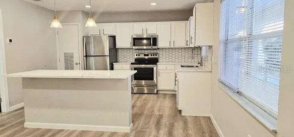 a kitchen with a refrigerator a stove top oven and white cabinets