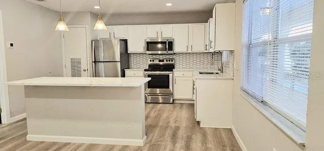 a kitchen with a refrigerator a stove top oven and white cabinets