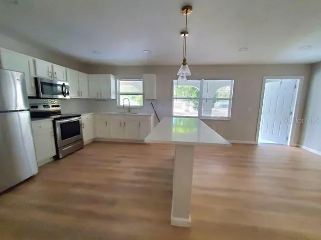 a kitchen with stainless steel appliances granite countertop a stove top oven a sink dishwasher and a refrigerator