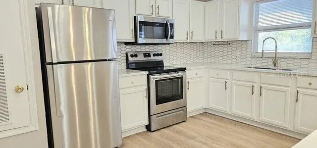 a kitchen with stainless steel appliances granite countertop a refrigerator sink and stove