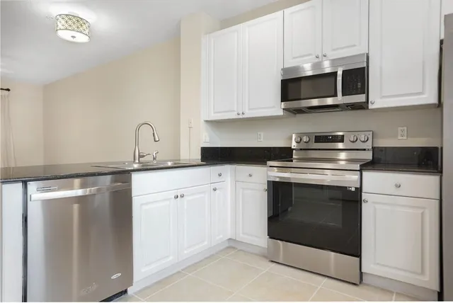 a kitchen with stainless steel appliances granite countertop a stove a microwave and a white cabinets