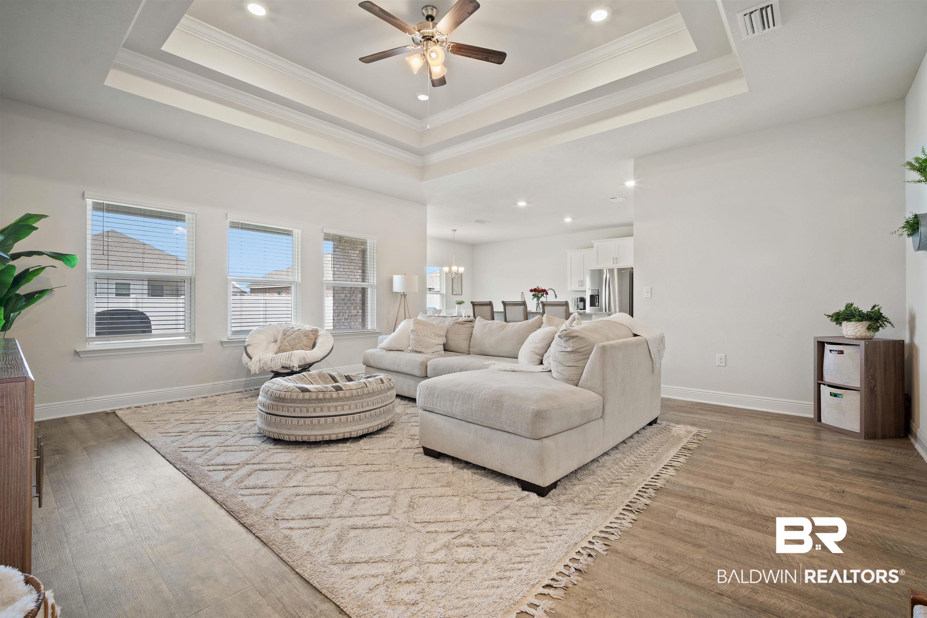 11021 Native Dancer Way Daphne, AL 36526 - Photo 4 of 35 Living area featuring a raised ceiling, wood finished floors, visible vents, and ceiling fan with notable chandelier