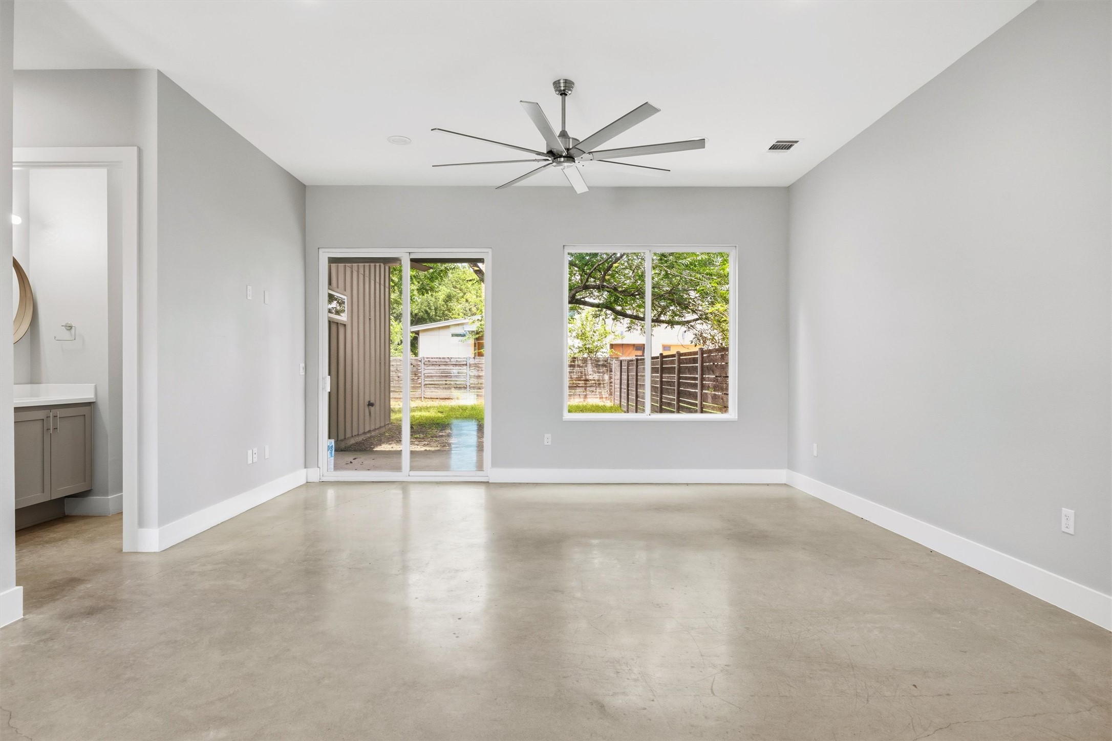 1210 Stobaugh Street, Unit B Austin, TX 78757 - Photo 34 of 40 A spacious, naturally illuminated room features a modern ceiling fan and direct outdoor access.