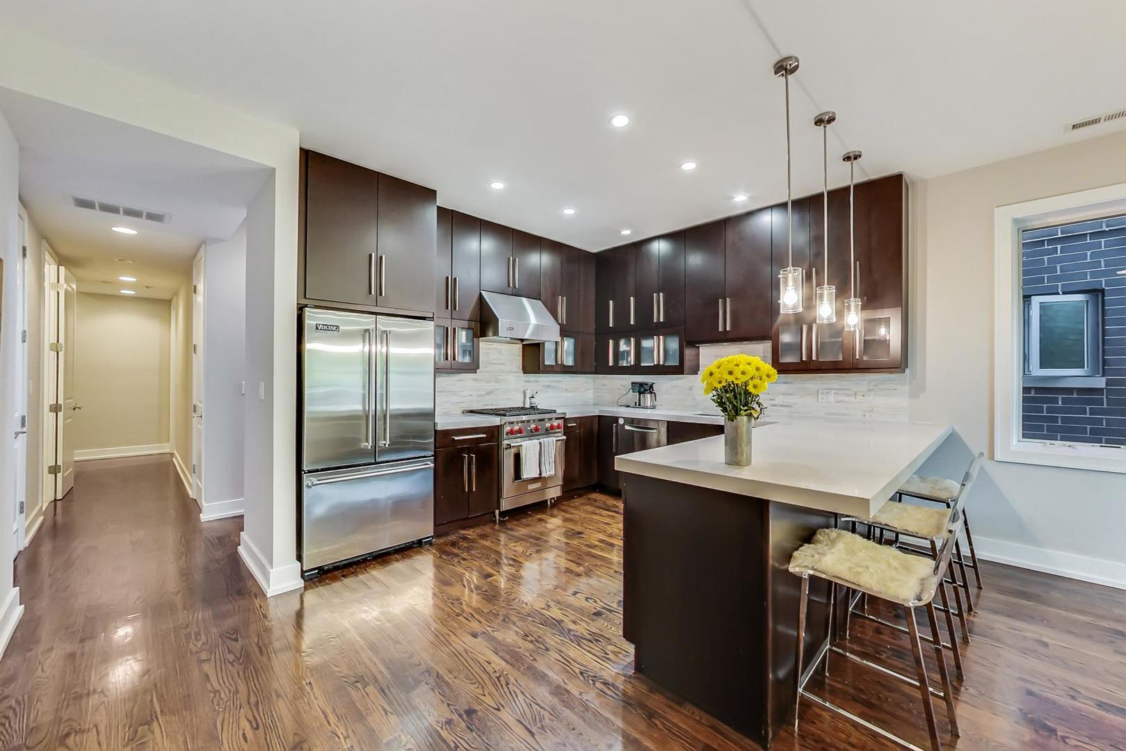 2144 West Rice Street, Unit 3E Chicago, IL 60622 - Photo 3 of 19 a kitchen with stainless steel appliances kitchen island granite countertop a refrigerator a sink a stove and a wooden floors