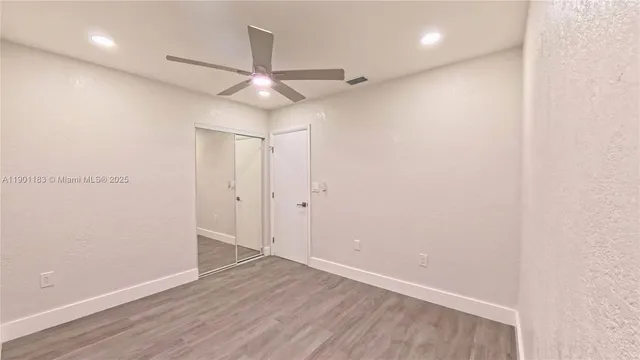 an empty room with wooden floor and a ceiling fan