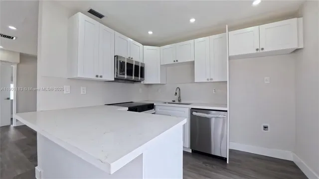 a kitchen with stainless steel appliances a stove a sink a microwave and cabinets