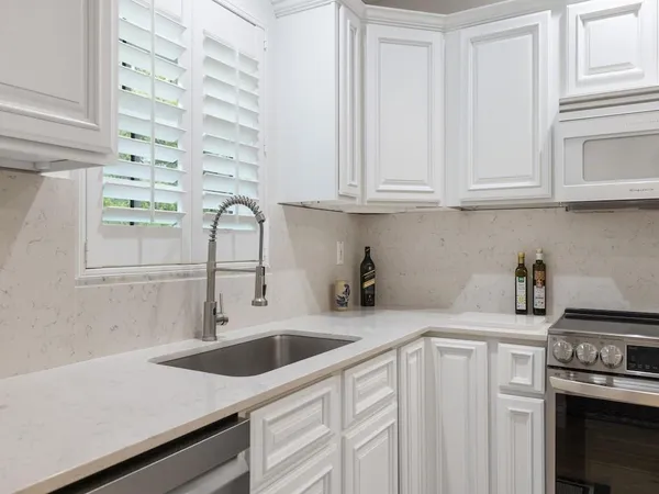 a kitchen with white cabinets and appliances