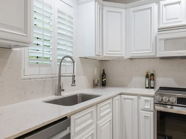 a kitchen with white cabinets and appliances