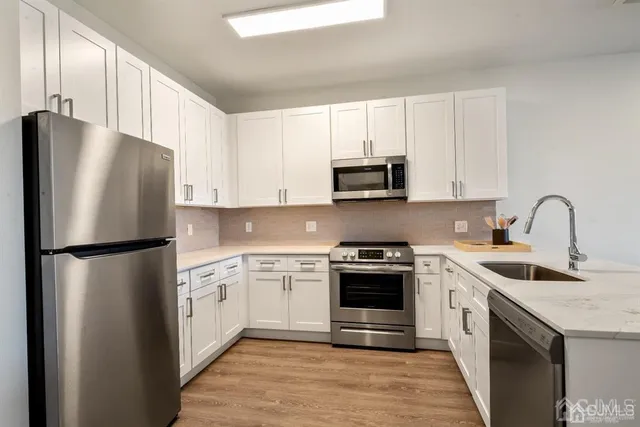 a kitchen with stainless steel appliances a refrigerator stove and white cabinets