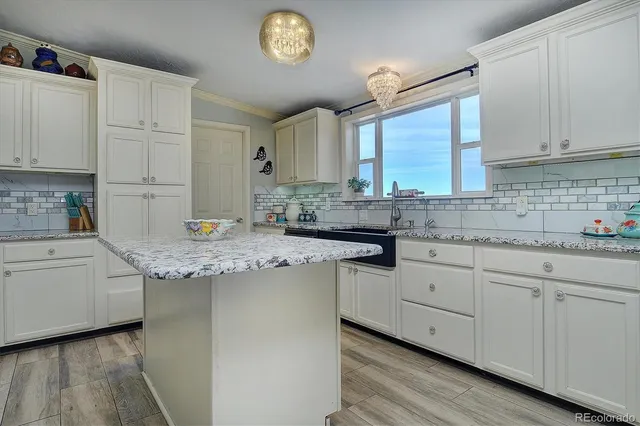 a kitchen with granite countertop white cabinets and a sink