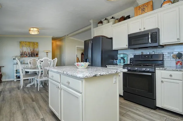 a kitchen with stainless steel appliances granite countertop a stove top oven a sink dishwasher and a refrigerator with wooden floor