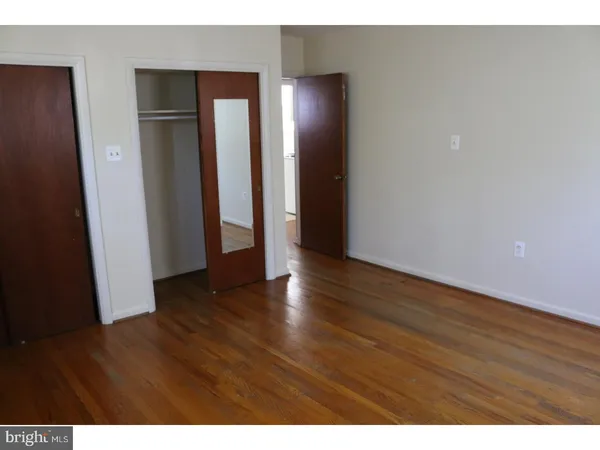 a view of an empty room with wooden floor and closet