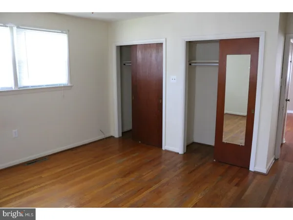 a view of an empty room with wooden floor and closet