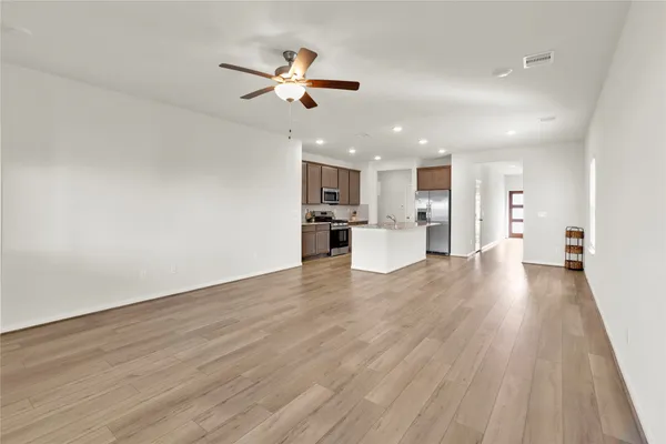 a view of kitchen with cabinets wooden floor and stainless steel appliances