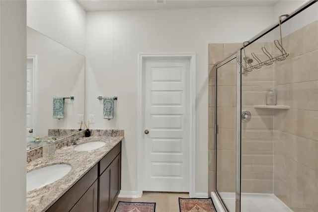 a bathroom with a granite countertop sink a shower and a mirror