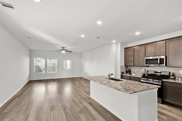 a large kitchen with stainless steel appliances granite countertop a stove a sink and a microwave