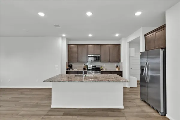 a large kitchen with stainless steel appliances granite countertop a sink a stove a refrigerator and a cabinets